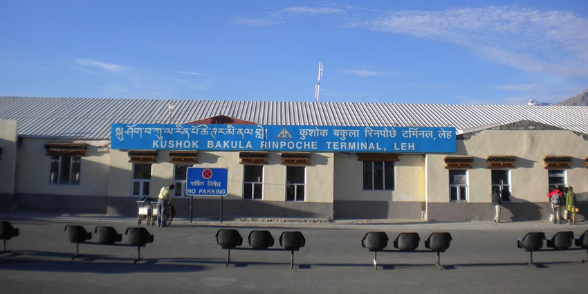 Kushok Bakula Rinpoche Airport building in Leh, with a blue sign under a clear blue sky.