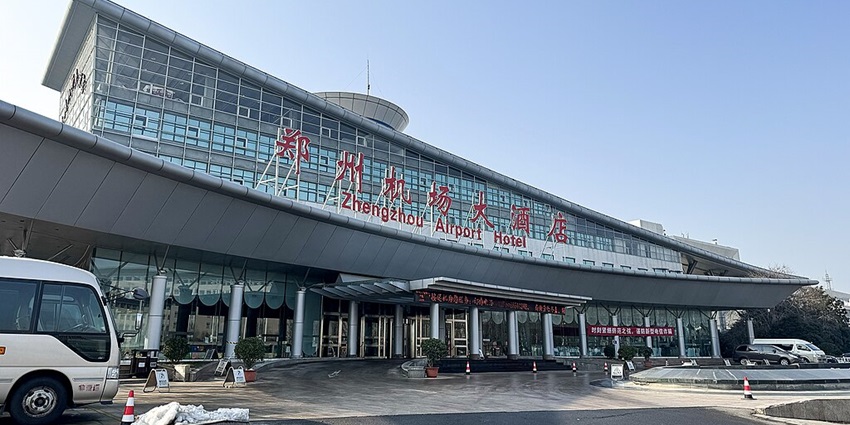 Modern Zhengzhou Airport with a sleek terminal, multiple runways, and parked aircraft