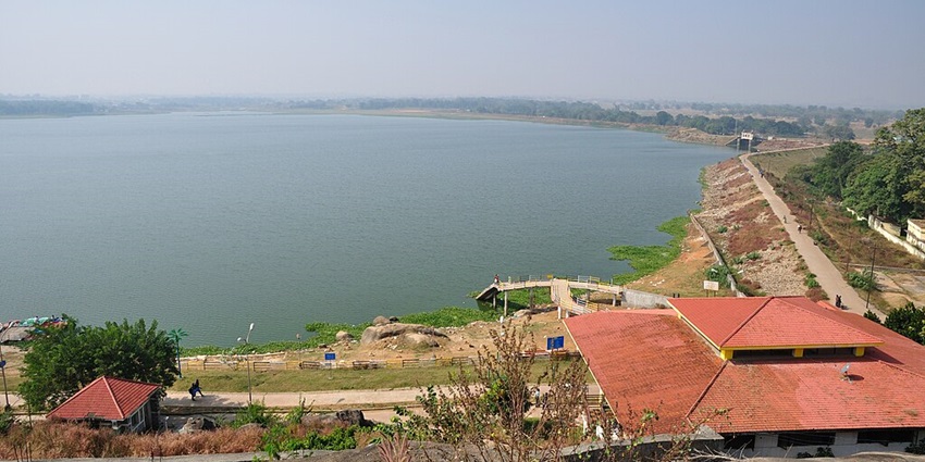 Dam lake with a large water body, sandy shores, buildings with red roofs and people