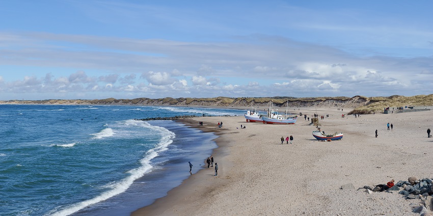 An image of Huk Beach showcasing the sandy shores and clear blue waters as people enjoy its scenery.