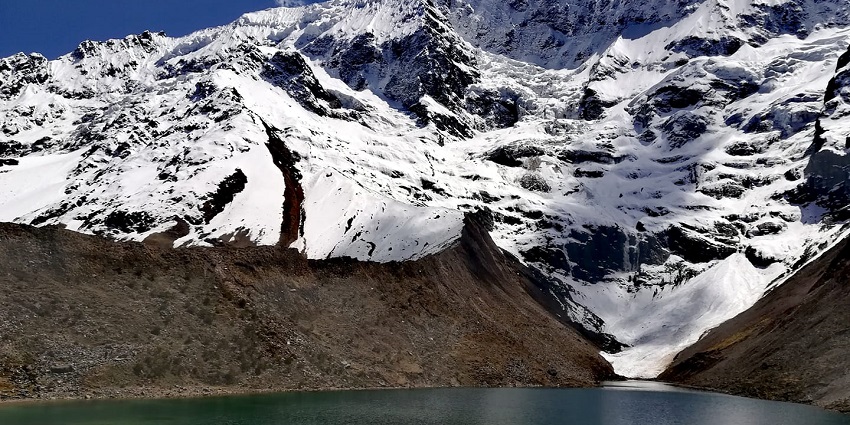 Scenic Humantay Lake on Salkantay trekking route reflecting snowy mountains.
