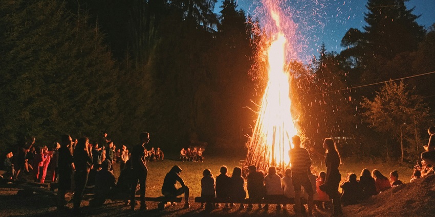 People sitting near a bonfire around the lake - one of the things to do at Pawna Lake.
