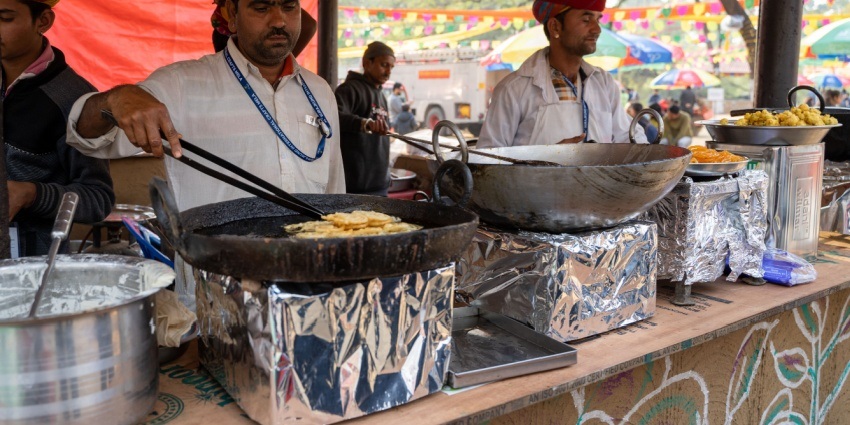 Smoke rises as a man fries delicious tikki(mashed potato pakora) at a street fast food stall.