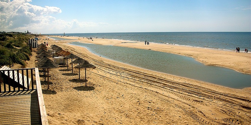 Image of Islantilla Beach around seashore under beautiful sky and people strolling around