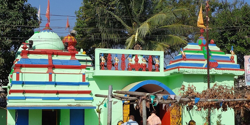 Colourfully painted goddess Mangala temple with people and a priest entering the temple