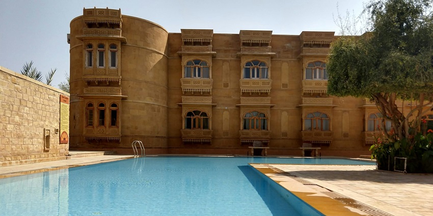 An image of the Jaisalmer Fort, made of golden stone, with the desert around it.