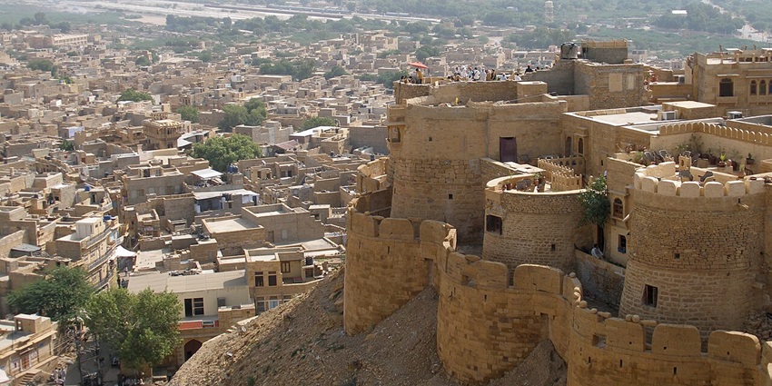 Golden sandstone ramparts of Jaisalmer Fort rising above the desert-flat cityscape.