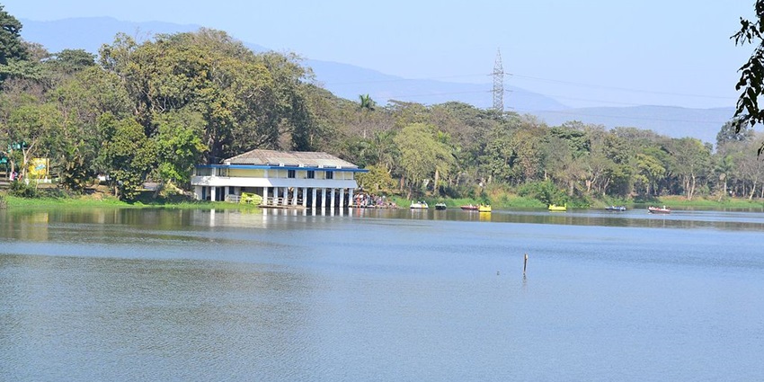 Jayanti Sarovar Lake with a white building near the lake, a tower and mountains afar