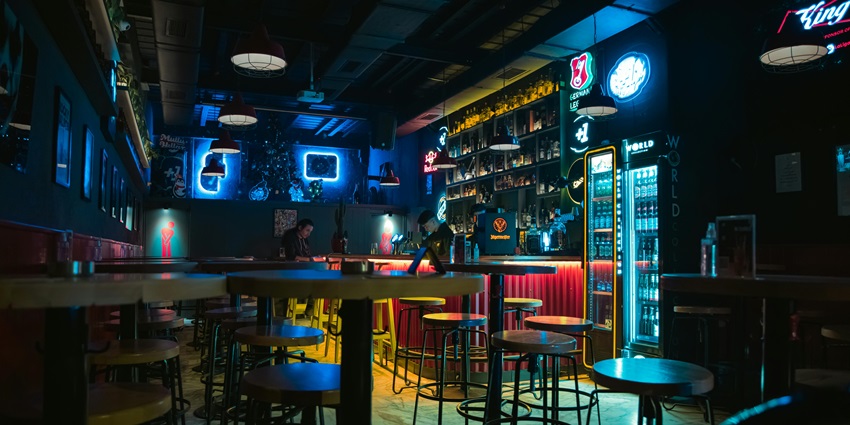 Image of interior of a bar with low dim lights and drinks on the side also seating area