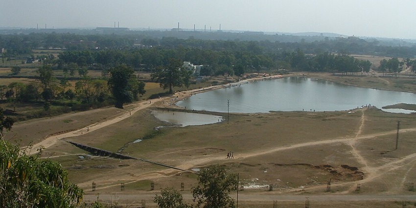 Lake from the top surrounded by the sandy shoreline, people walking and green trees
