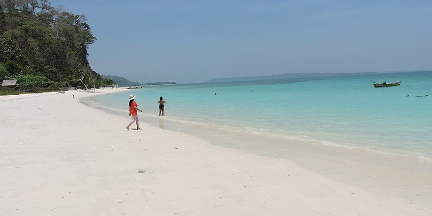 White sandy shore of Kalapathar Beach with turquoise waters and scattered black rocks