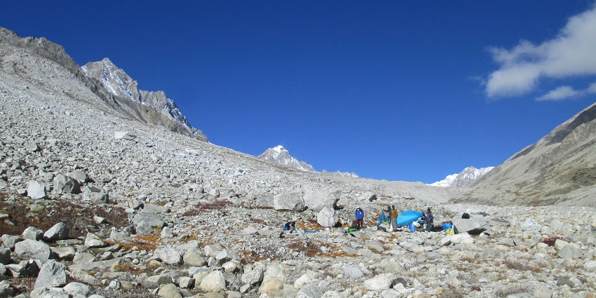 An image of Kalindi Pass Trek in Uttarakhand with several people setting up a camp