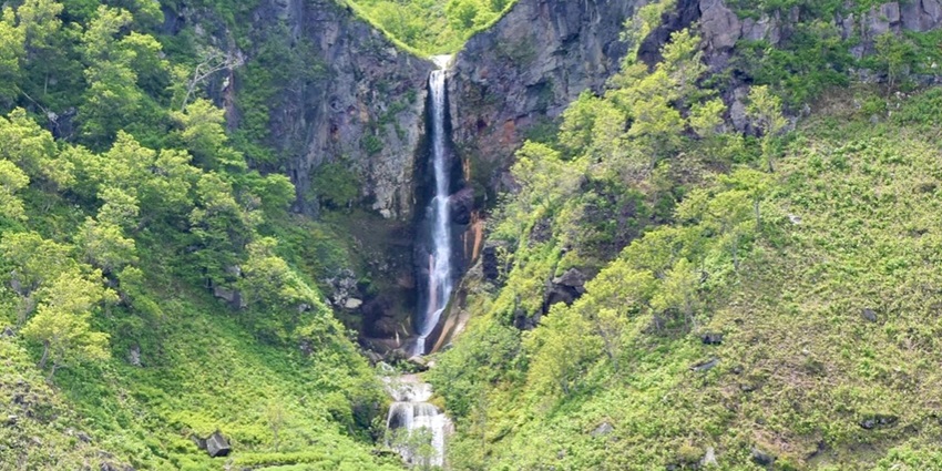 Natural hot spring waterfall amid stunning Shiretoko landscapes.