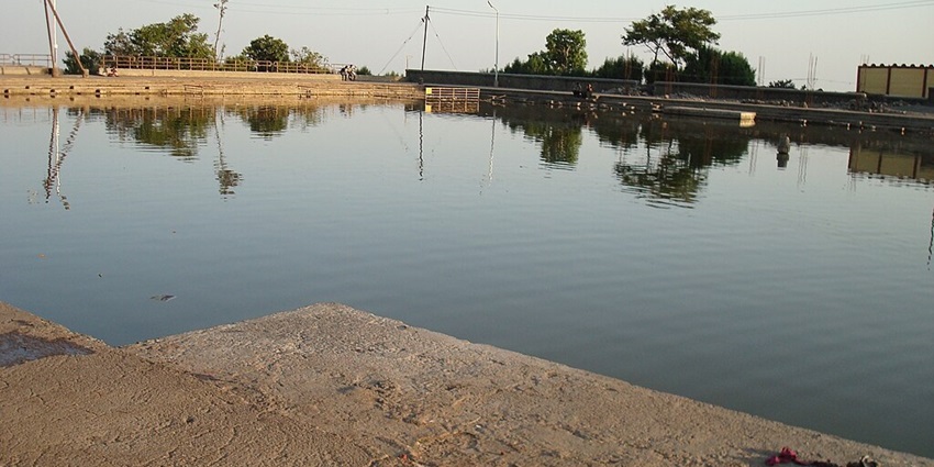 Lake with concrete steps, electricity wire poles and street lights in the borders