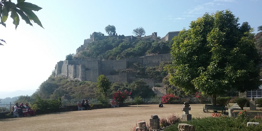 An image of the ancient stone fortress of Kangara, with a large wooden gate, situated on a hillside, the most significant of the historical forts in India.