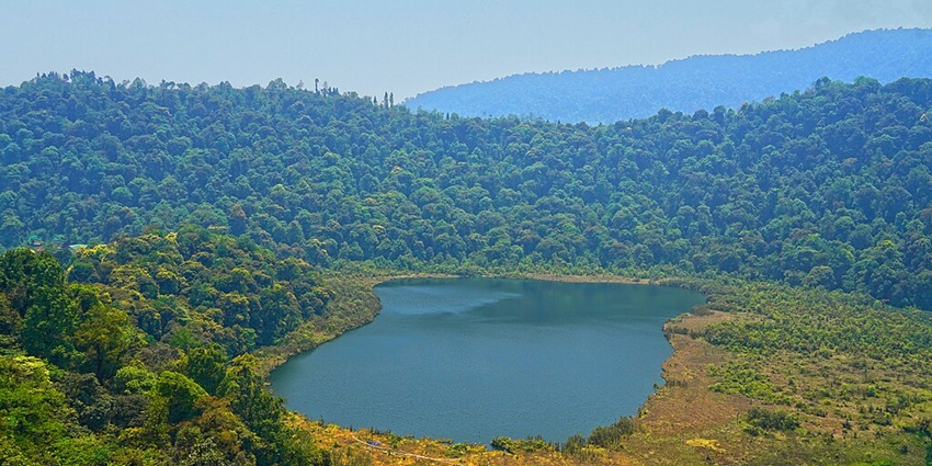 Khecheopalri Lake with a small water body surrounded by dense greenery and hills.