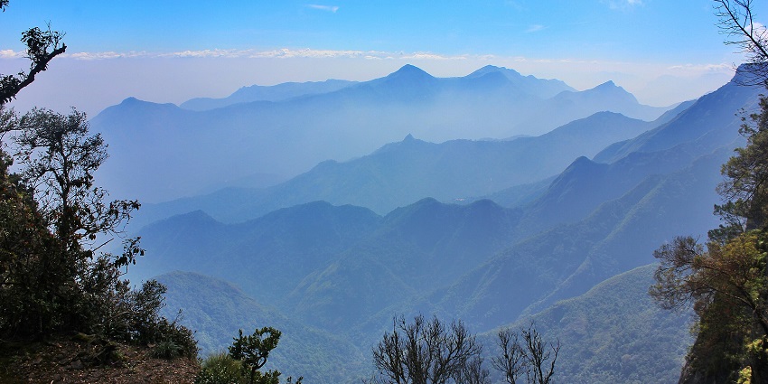 An image of the scenic view of layered mountains in Kodaikanal under a clear sky.