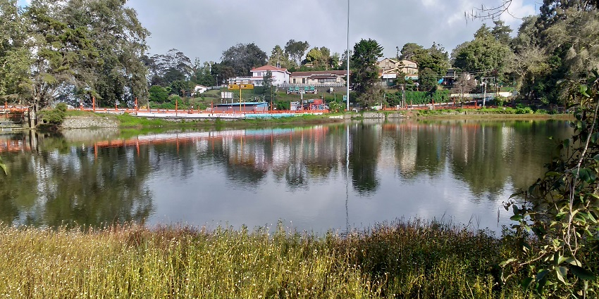 An image of Kodaikanal Lake in Tamil Nadu with boating facilities and mist-covered hills.