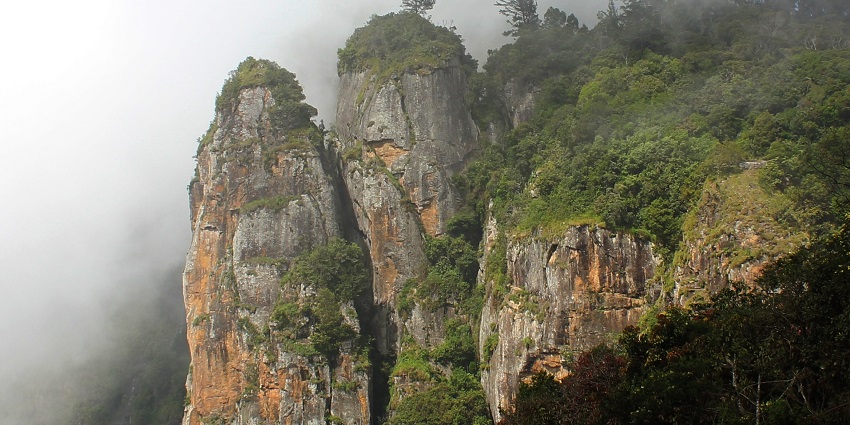 Popular twin pillar rocks are covered in mist at Kodaikanal hill station, as mentioned in the Tamil Nadu travel guide.