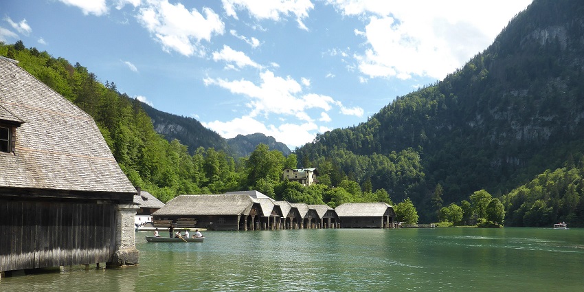 An image Königssee lake with wooden buildings, people on a boat and greenery around
