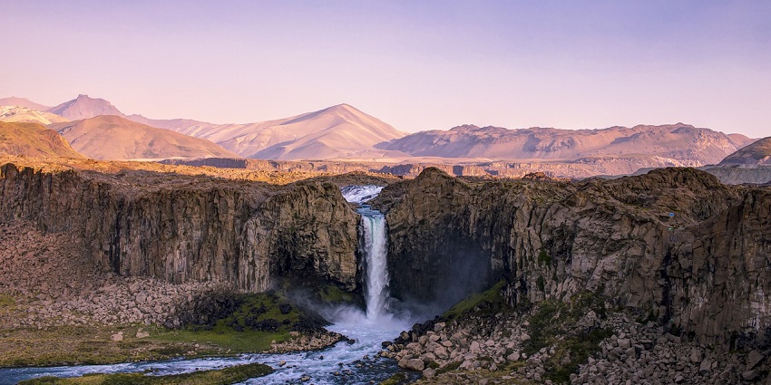 An image of a waterfall flowing through mountains with water similar to Kunchikal Falls