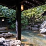 Image of hot bath at Kyoto Hot Springs, surrounded by lush greenery landscape