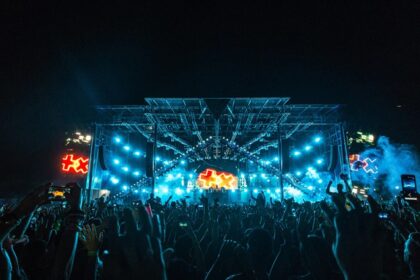 A vibrant nightlife scene at an outdoor music festival, with a massive illuminated stage