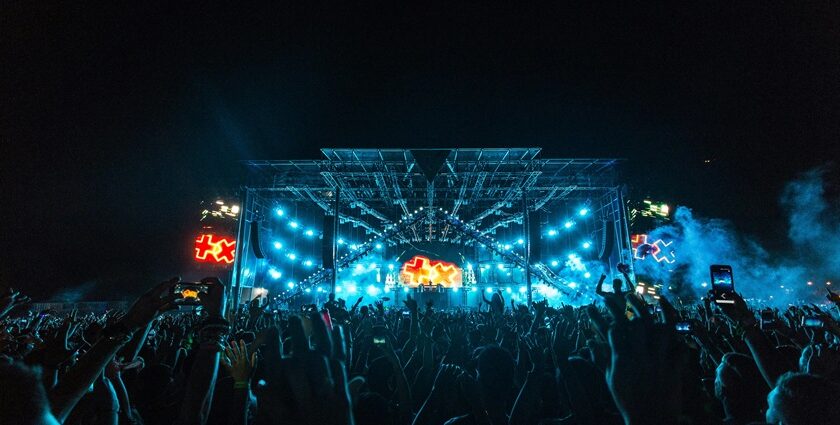 A vibrant nightlife scene at an outdoor music festival, with a massive illuminated stage