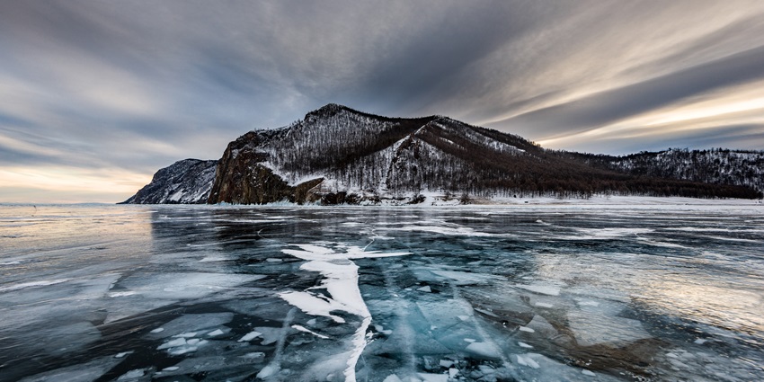 Lake Baikal with a frozen glass water body and dry trees - one of the lakes in Asia.