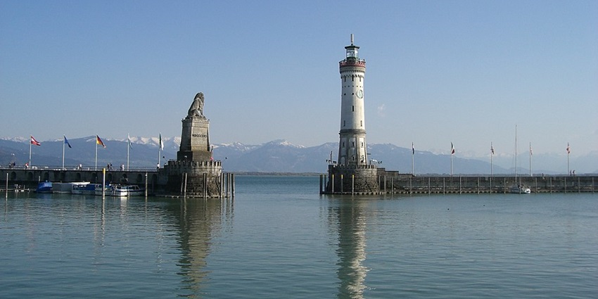 An image view of Lake Constance with calm waters, boats, and the historic Lindau lighthouse