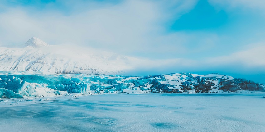 Buried frozen lake under the ice with mountains covered with heavy snow in the back