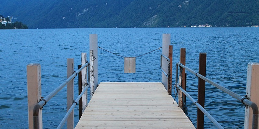 An image view of Lugano Lake in Switzerland with serene waters, surrounding mountains