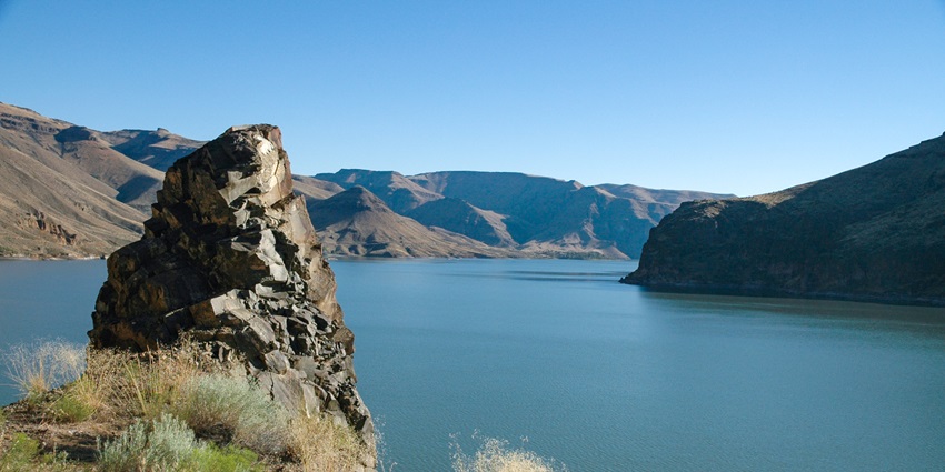 A rock structure at a ledge with a backdrop of Lake Owyhee in Malheur County, Oregon.