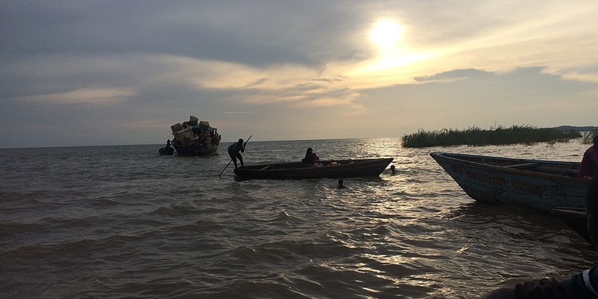 An image view of Lake Tanganyika at sunset with golden hues, calm waters, and lakes in Africa