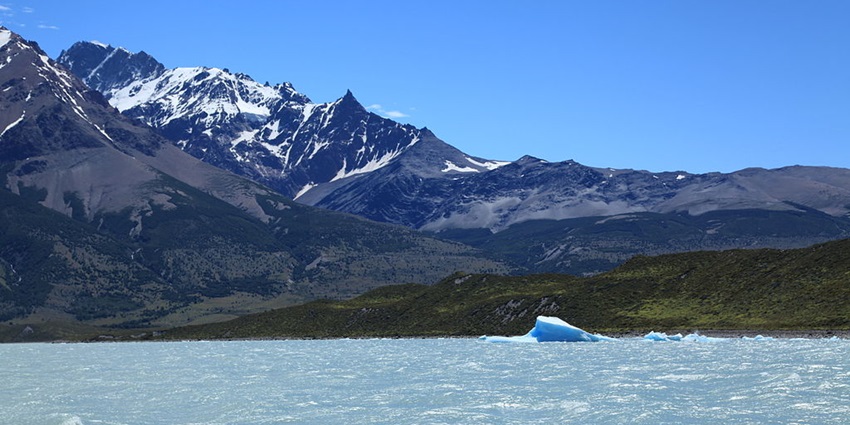 A serene lake with mountains and a bright sky suggests a perfect spot for relaxation.