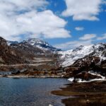 Changu Lake in North Sikkim with people standing on the shore and snow-covered mountains.