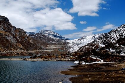 Changu Lake in North Sikkim with people standing on the shore and snow-covered mountains.