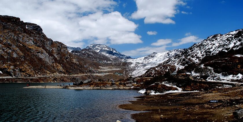 Changu Lake in North Sikkim with people standing on the shore and snow-covered mountains.