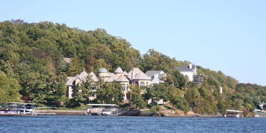 Lake of the Ozarks with MO houses surrounded by greenery and multiple piers by the lake