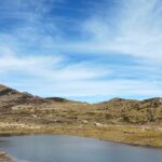 One of the lakes in Arunachal Pradesh, featuring pristine water, is surrounded by lush greenery and mountains.