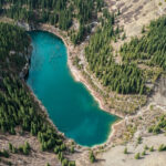 An image of Kandy Lake in Kazakhstan surrounded by rocky shorelines and lush greenery.