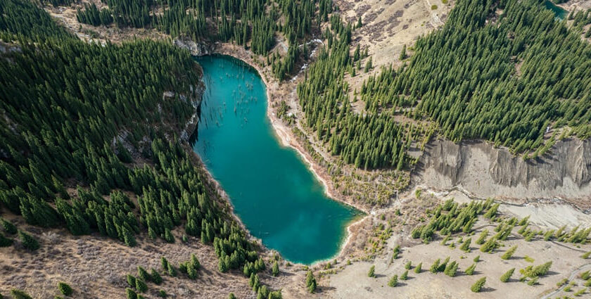 An image of Kandy Lake in Kazakhstan surrounded by rocky shorelines and lush greenery.