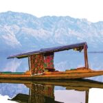 Dal Lake in Srinagar with shikaras, houseboats, and a picturesque mountain backdrop.