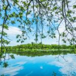 An image of Twin lakes in Missouri with the reflection of the clear blue sky and trees