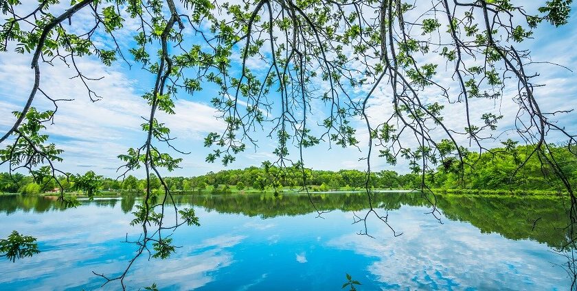 An image of Twin lakes in Missouri with the reflection of the clear blue sky and trees