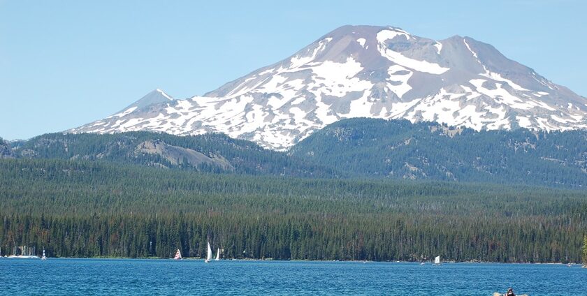 A couple paddles while boating in Oregon’s Elk Lake with South Sister in the background.