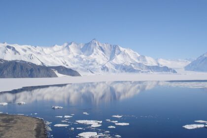 Lake in Antarctica surrounded by white snow and snowy mountains in the background