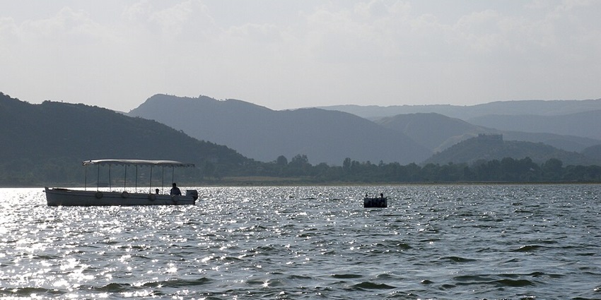 Sunlight reflects on the surface of a lake while a boat passes by on a sunny day.