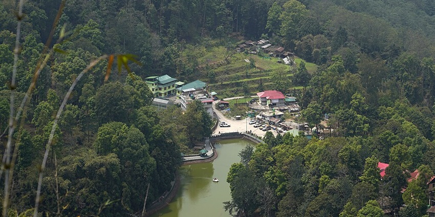 Lam Pokhari passing through the greenery with the vehicles parked and multiple buildings.