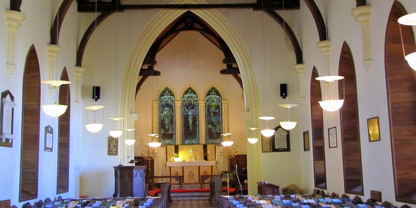 Interior of St. Paul's Church in Landour, featuring wooden pews and stained glass windows